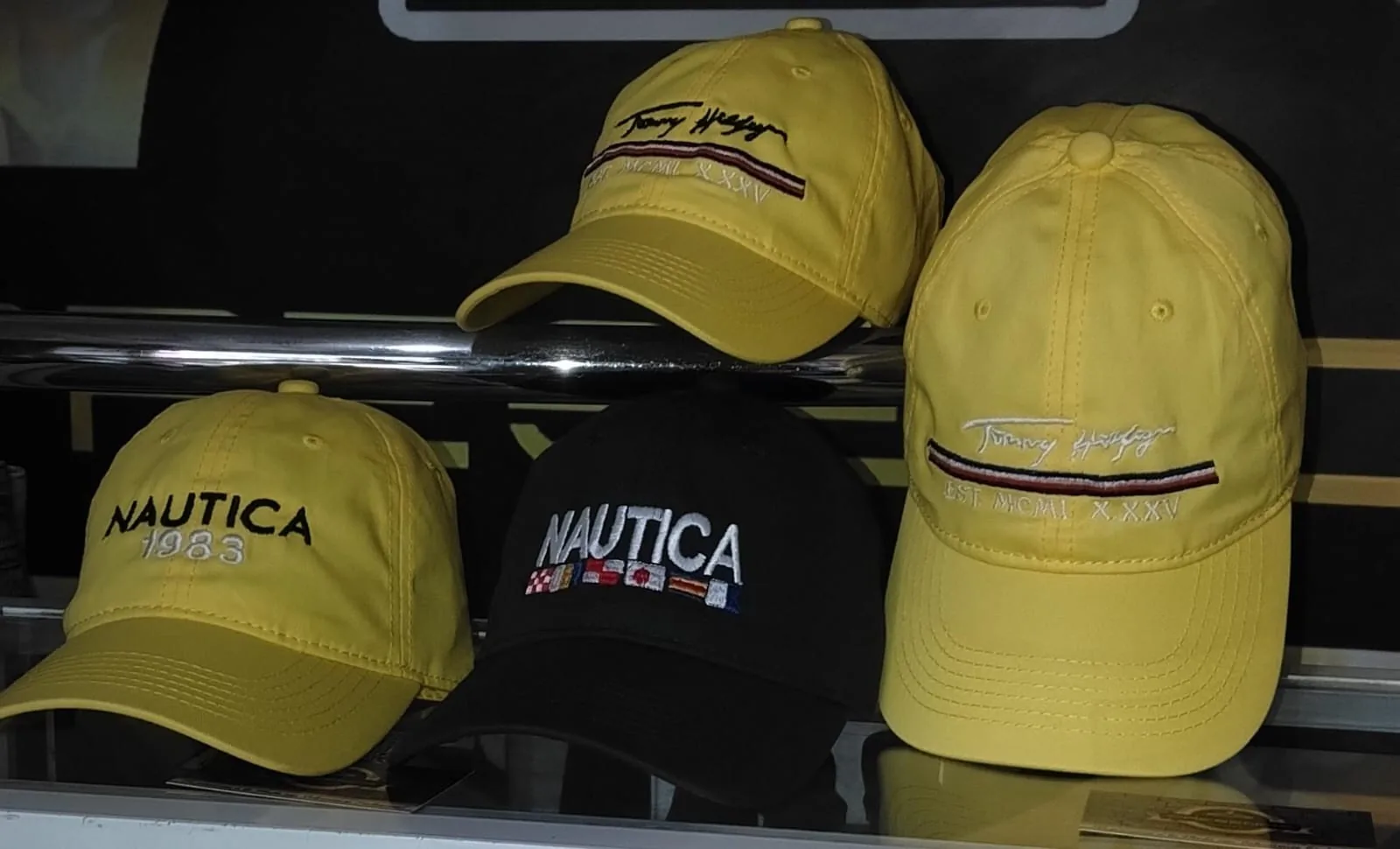 Gorras en estante Nautica y Tommy Hilfiger: 2 amarillas, amarilla Nautica 1983, negra Nautica, disponibles en PRESENCIA, Cartagena